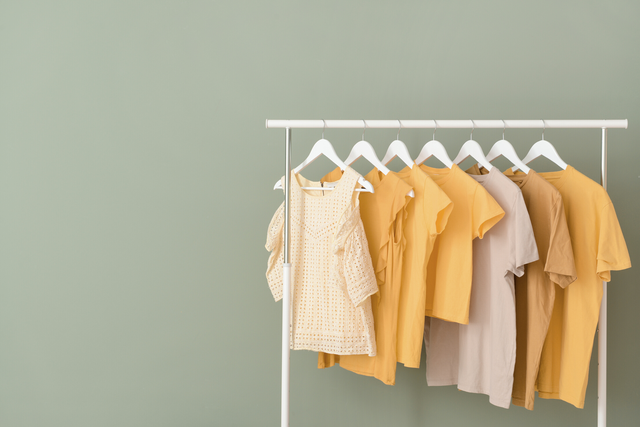 Rack with Hanging Clothes on Color Background